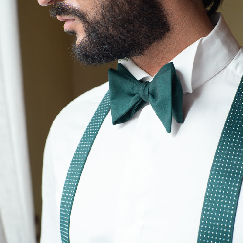 Papillon verde scuro annodato su camicia bianca, dettaglio collo