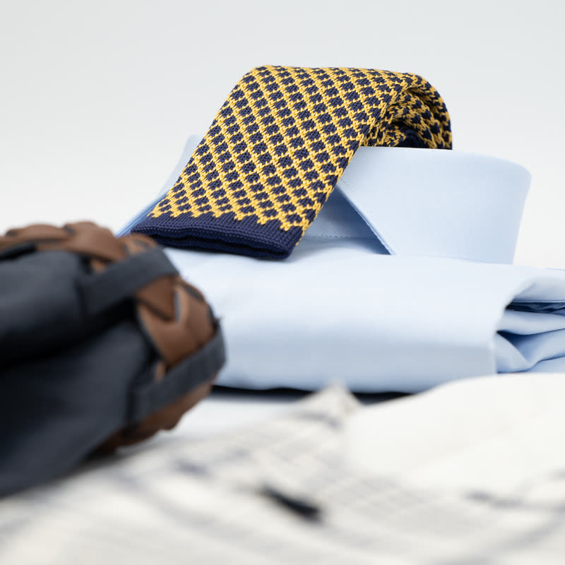 Cravatta a maglia blu e gialla su camicia azzurra, dettaglio polso