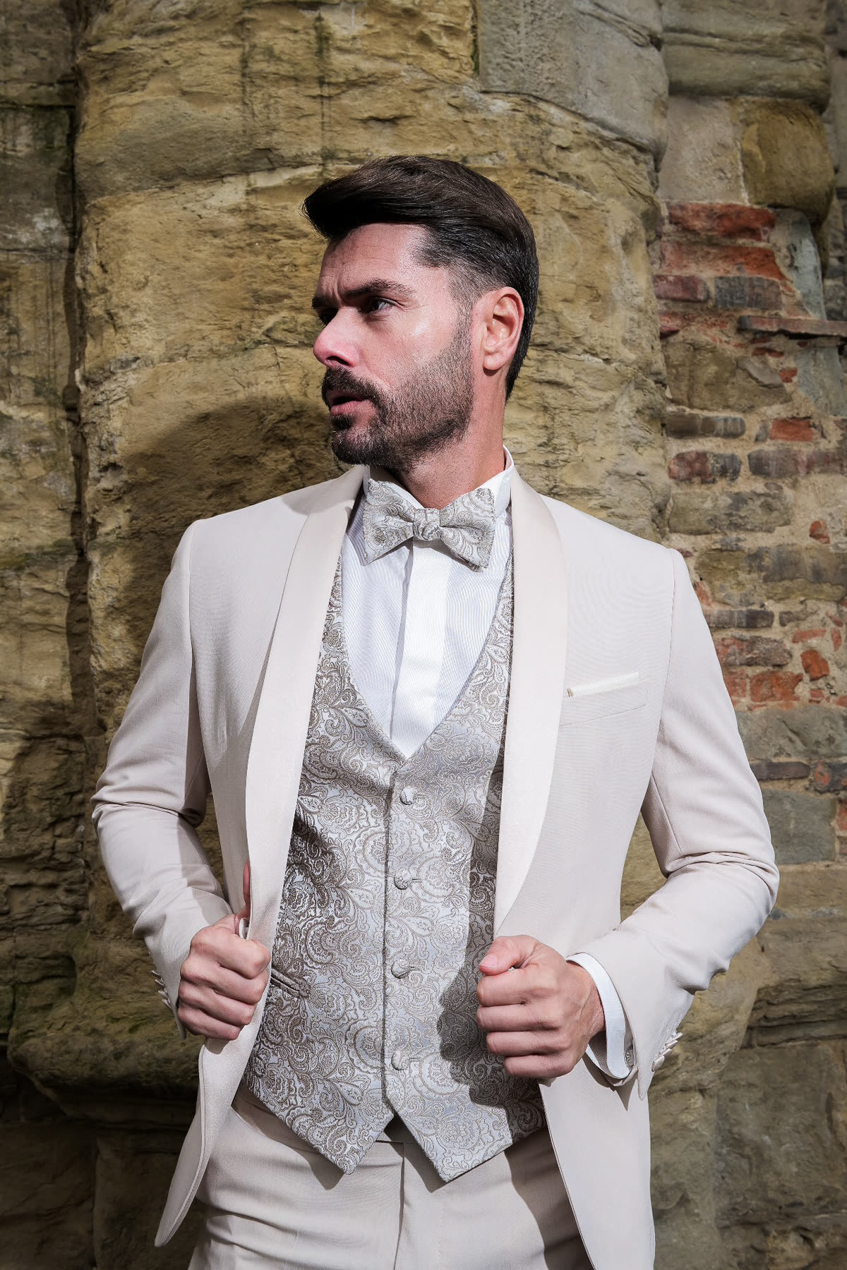 Uomo con smoking color panna e gilet broccato, cerimonia elegante